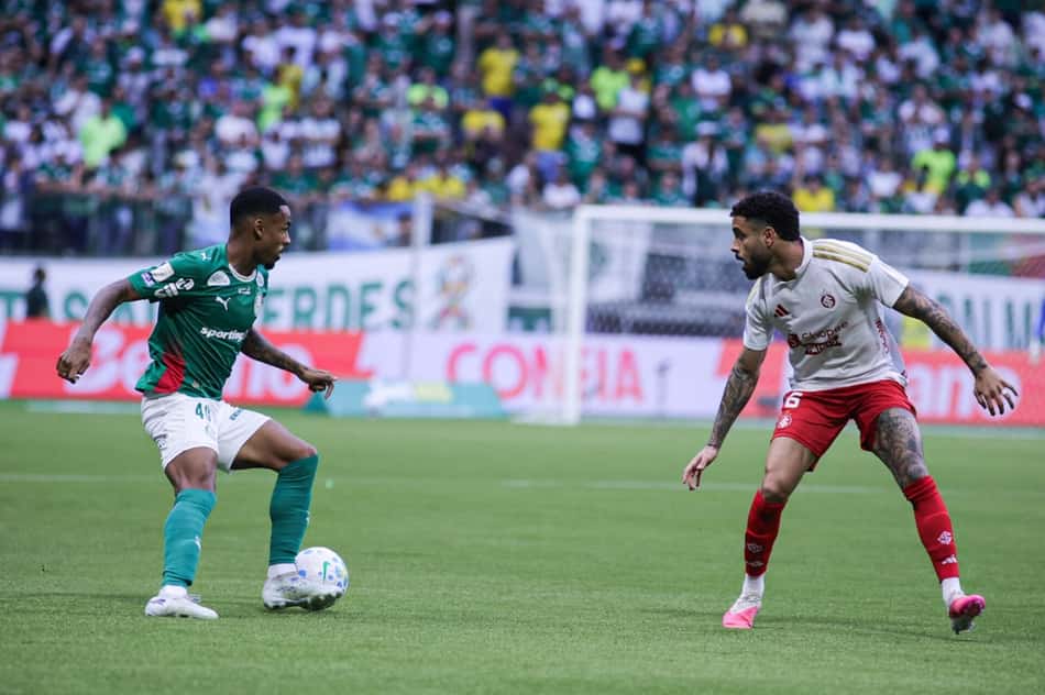 Allan controla a bola durante a partida entre Palmeiras e Internacional no Nubank Parque O jogador Allan, do Palmeiras, vestindo o uniforme verde tradicional, controla a bola no meio-campo enquanto é marcado de perto por um atleta do Internacional, de uniforme branco e vermelho. Ao fundo, arquibancadas cheias com a torcida alviverde.
