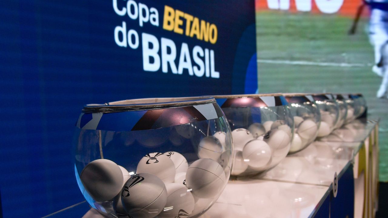 Potes com as bolinhas para o sorteio das quartas de final da Copa do Brasil Potes de vidro alinhados contendo as bolinhas brancas do sorteio. Ao fundo, um painel azul com o logotipo da Copa Betano do Brasil.